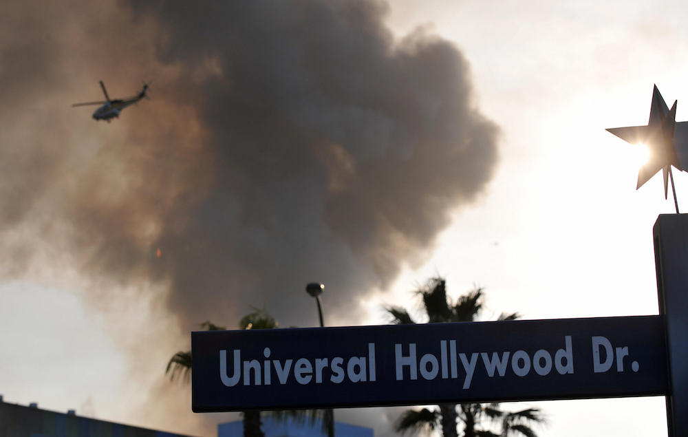 A helicopter flies over burning structur