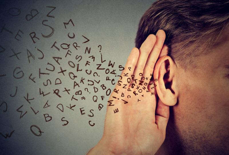 man holds hand near ear listens carefully alphabet letters flying in